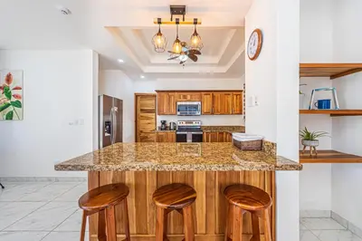 a kitchen with a island with three stools at Casa Paraiso de Ballenas in Uvita