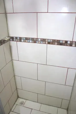 a bathroom with a shower with white tiles at Hotel El Dorado in San José