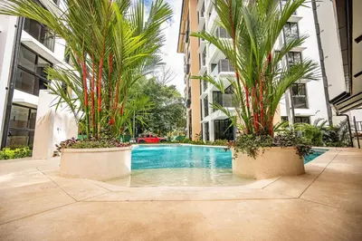a swimming pool in the middle of a building with palm trees at Torres del Mar oceanview 6th-floor two-bedroom condo in Jacó