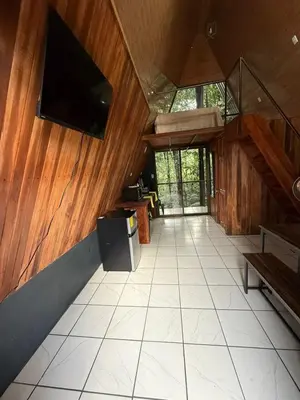 a living room with a tv on a wooden wall at El Nido del Tucan Rio Celeste in El Achiote