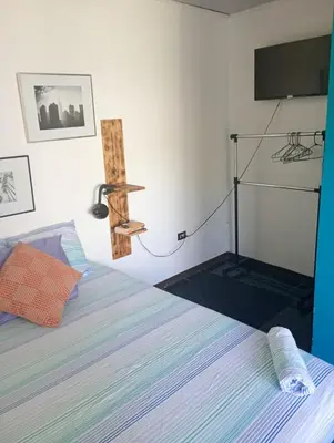 a bedroom with a bed with a tv on the wall at Kristel Rooms in Quepos
