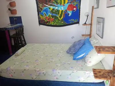 a bed in a room with a painting on the wall at Kristel Rooms in Quepos