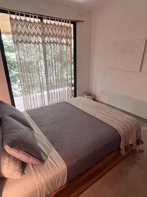 a bed in a bedroom with a large window at Ona Casita 1 in Cuajiniquil