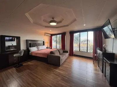 a bedroom with a bed and a couch and a television at Condomínio Vistas del Rio in San Antonio