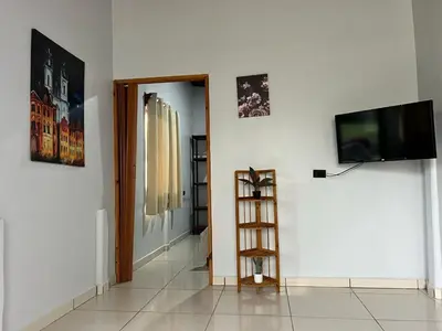 a living room with a television and a white wall at Teyú Green Cottage in Cuatro Esquinas