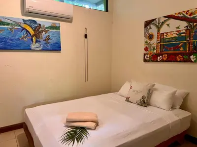 a bedroom with a white bed with a painting on the wall at Zen Zaru Free MA Park Tour & Breakfast in Manuel Antonio