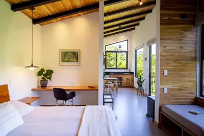 a bedroom with a bed and a desk and chairs at MAUMA Forest Villas - Fireplace & Amazing Views in Monteverde Costa Rica