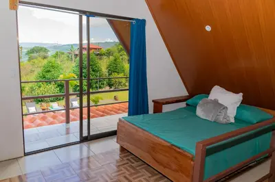 a bedroom with a bed and a large window at Bongalows Chepe Araya in Pejibaye