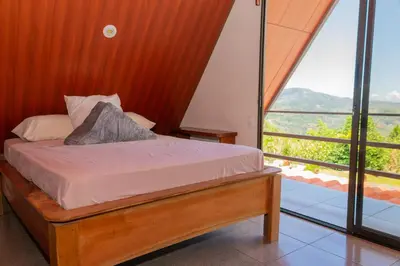 a bedroom with a bed and a large window at Bongalows Chepe Araya in Pejibaye