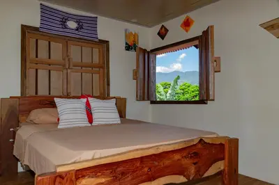 a bedroom with a large bed with a window at Cabaña Rustica Chepe Araya in Pejibaye