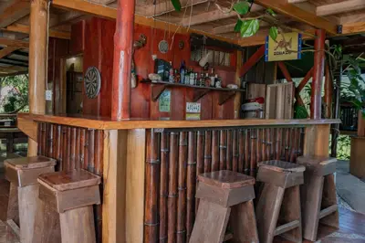 a bar with wooden stools in a room at Cabaña Rustica Chepe Araya in Pejibaye