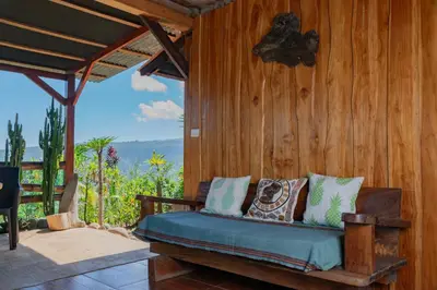 a porch with a bed on a wooden wall at Cabaña Rustica Chepe Araya in Pejibaye