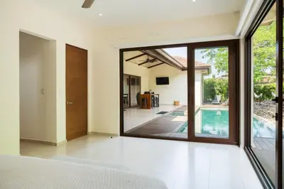 a bedroom with a large glass door and a swimming pool at La Perla Cozy 3BR sleeps 10 Hacienda Pinilla in Santa Cruz