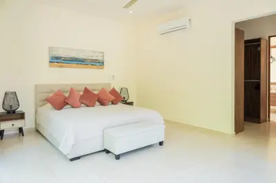a white bedroom with a white bed with red pillows at La Perla Cozy 3BR sleeps 10 Hacienda Pinilla in Santa Cruz
