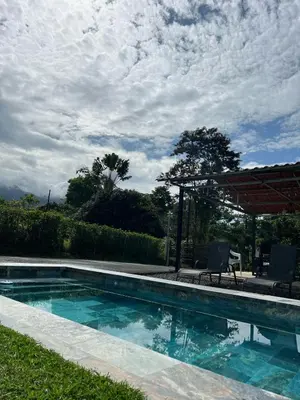 a swimming pool with two chairs and an umbrella at Quinta La Esperanza in Chachagua