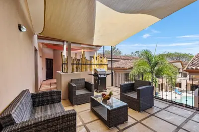 an outdoor patio with wicker chairs and a grill at 2 BD Condo with Pool in Ocotal