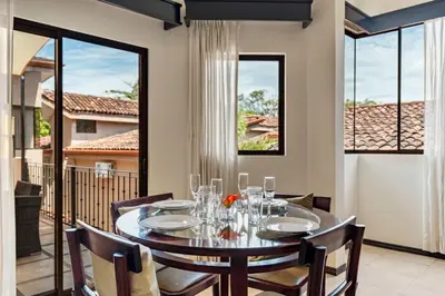 a dining room with a table and chairs and windows at 2 BD Condo with Pool in Ocotal