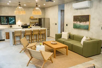 a living room with a green couch and a kitchen at Manuel Antonio Tree House Villas - 3 Bedrooms in Quepos