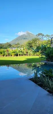 a pond with a mountain in the background at Xanadu Arenal Villa in Fortuna