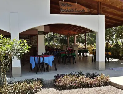 a restaurant with tables and chairs on a patio at Hotel Pochote Grande in Jacó