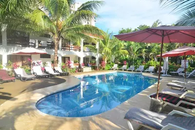 a swimming pool with chairs and umbrellas in a resort at Hotel Pochote Grande in Jacó