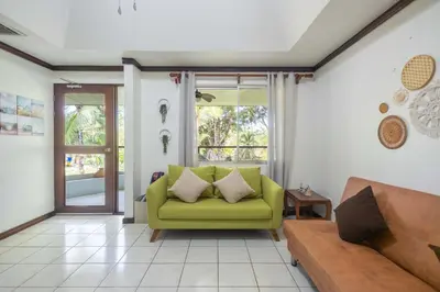 a living room with a green couch and a window at Casa del Sol - Poolside Villa in Quepos