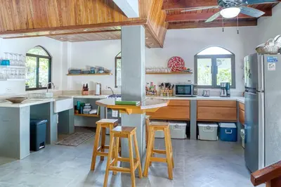 a kitchen with wooden counter stools and a refrigerator at Mariposa Monarca in Esterillos