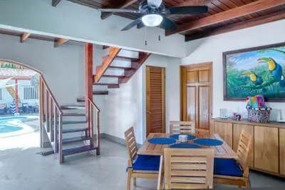 a dining room with a table and a staircase at Mariposa Monarca in Esterillos