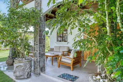 a patio with a chair and a couch and trees at Mariposa Monarca in Esterillos