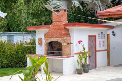 a brick oven in a yard with a house at Casa Mariposa in Esterillos