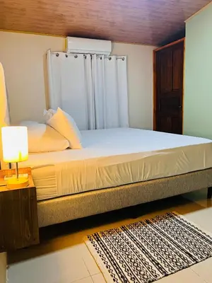 a large bed in a room with a lamp on a table at Arenal Harmony-Acogedor Apartamento-La Fortuna in Fortuna