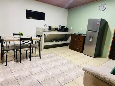 a kitchen with a table and a refrigerator and a table and chairs at Arenal Harmony-Acogedor Apartamento-La Fortuna in Fortuna