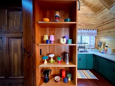 a kitchen with wooden shelves with different colored cups at Cabaña Nora in Cedral