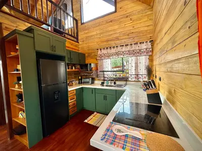 a kitchen with a green refrigerator and wooden walls at Cabaña Nora in Cedral