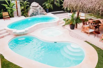 a swimming pool with a spa in the middle of a yard at Bahia Selvatica Lodge in Uvita