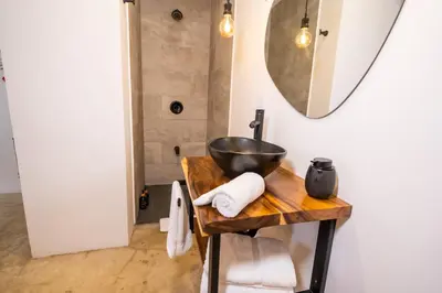 a bathroom with a sink and a bowl on a wooden table at Bahia Selvatica Lodge in Uvita