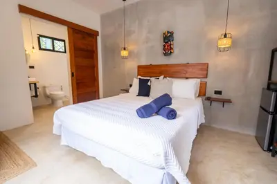 a bedroom with a large white bed with blue pillows at Bahia Selvatica Lodge in Uvita
