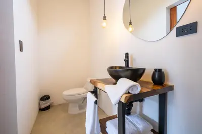 a bathroom with a sink and a toilet and a mirror at Bahia Selvatica Lodge in Uvita