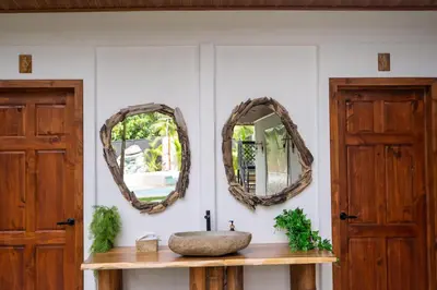 a bathroom with two mirrors and a sink at Bahia Selvatica Lodge in Uvita