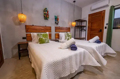 a bedroom with two beds with white sheets at Bahia Selvatica Lodge in Uvita