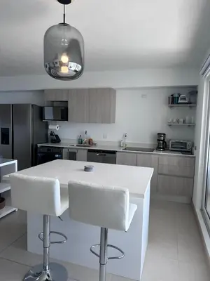 a kitchen with a white counter and white chairs at 16th Floor Oceanview Bliss in Jacó