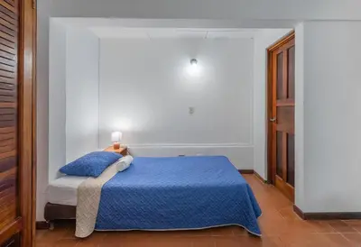 a bedroom with a bed with a blue comforter at Hotel el Tajalin in Montezuma
