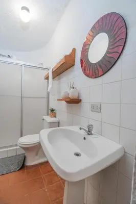 a bathroom with a sink and a mirror and a toilet at Hotel el Tajalin in Montezuma