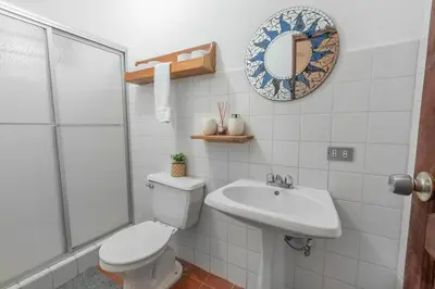 a bathroom with a toilet and a sink and a mirror at Hotel el Tajalin in Montezuma
