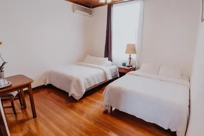 a bedroom with two beds and a table and a desk at Hotel Dunn Inn in San José