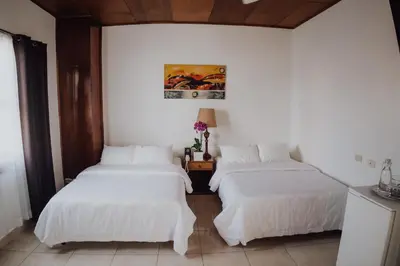 two beds in a room with white walls at Hotel Dunn Inn in San José