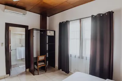 a room with a bed and a chair and a window at Hotel Dunn Inn in San José