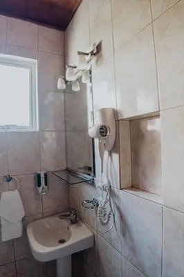 a small bathroom with a sink and a shower at Hotel Dunn Inn in San José
