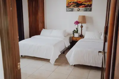 two beds in a room with white sheets and a table at Hotel Dunn Inn in San José