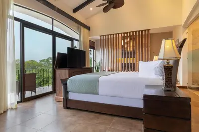 a bedroom with a bed with a television and a balcony at Villa Buena Onda All Inclusive in Coco